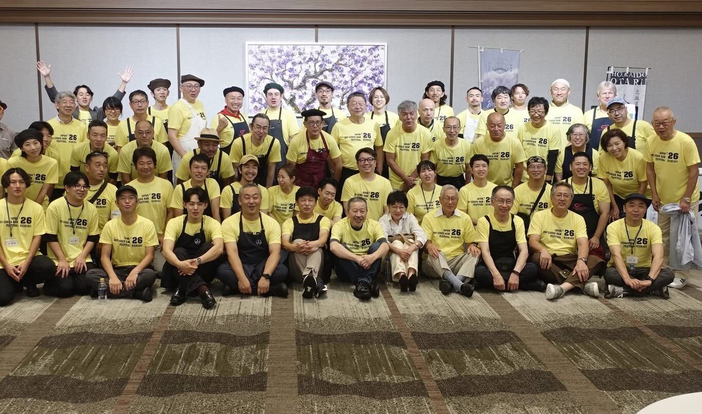 国産生ハムフェスティバルの会場で、黄色いTシャツを着た参加者の集合写真